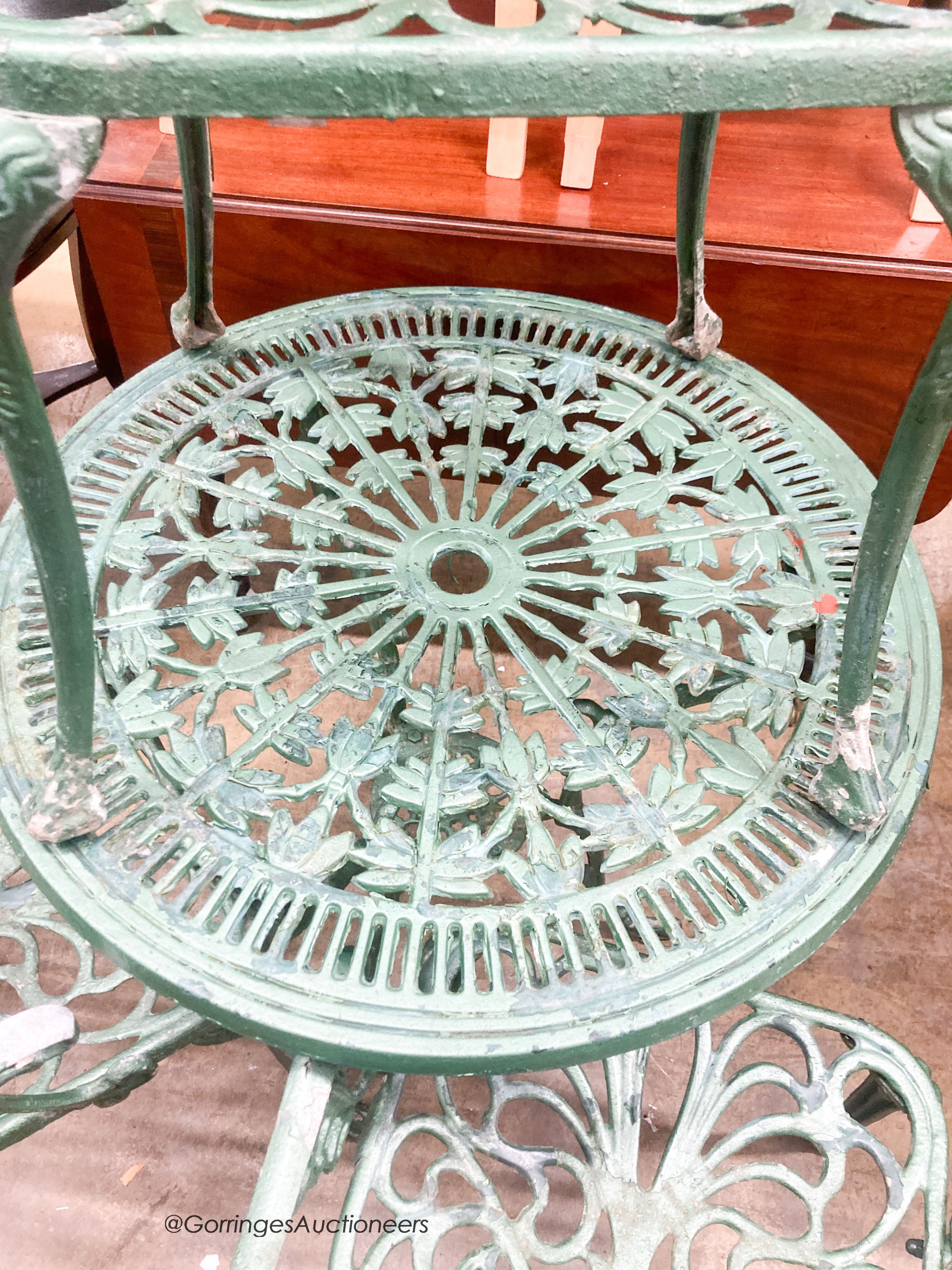 A cast painted aluminium circular garden table, diameter 69cm together with three similar elbow chairs